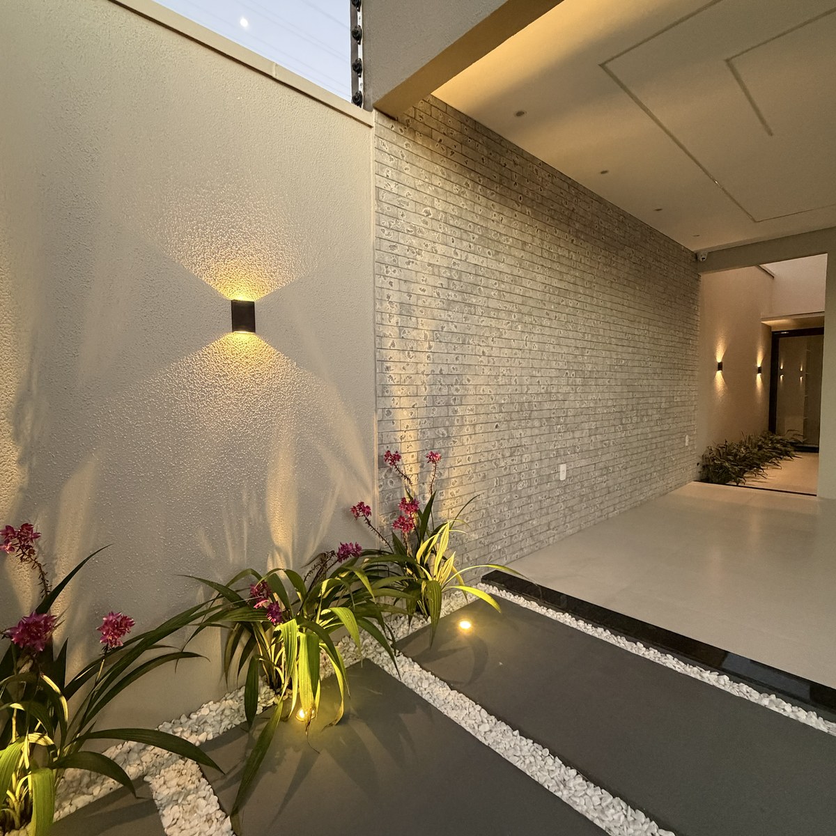 Entrada da casa com jardim e iluminação